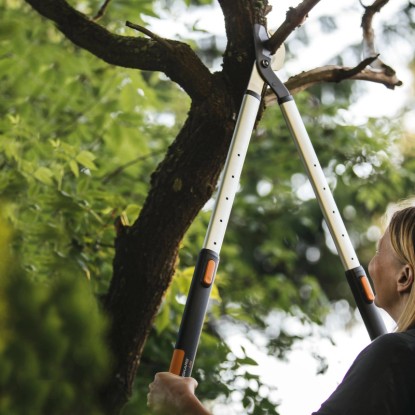 Teleskopické nožnice na konáre Fiskars SmartFit L86 strihajú konár v záhrade. Teleskopické nožnice na konáre Fiskars SmartFit L86 strihajú konár v záhrade.