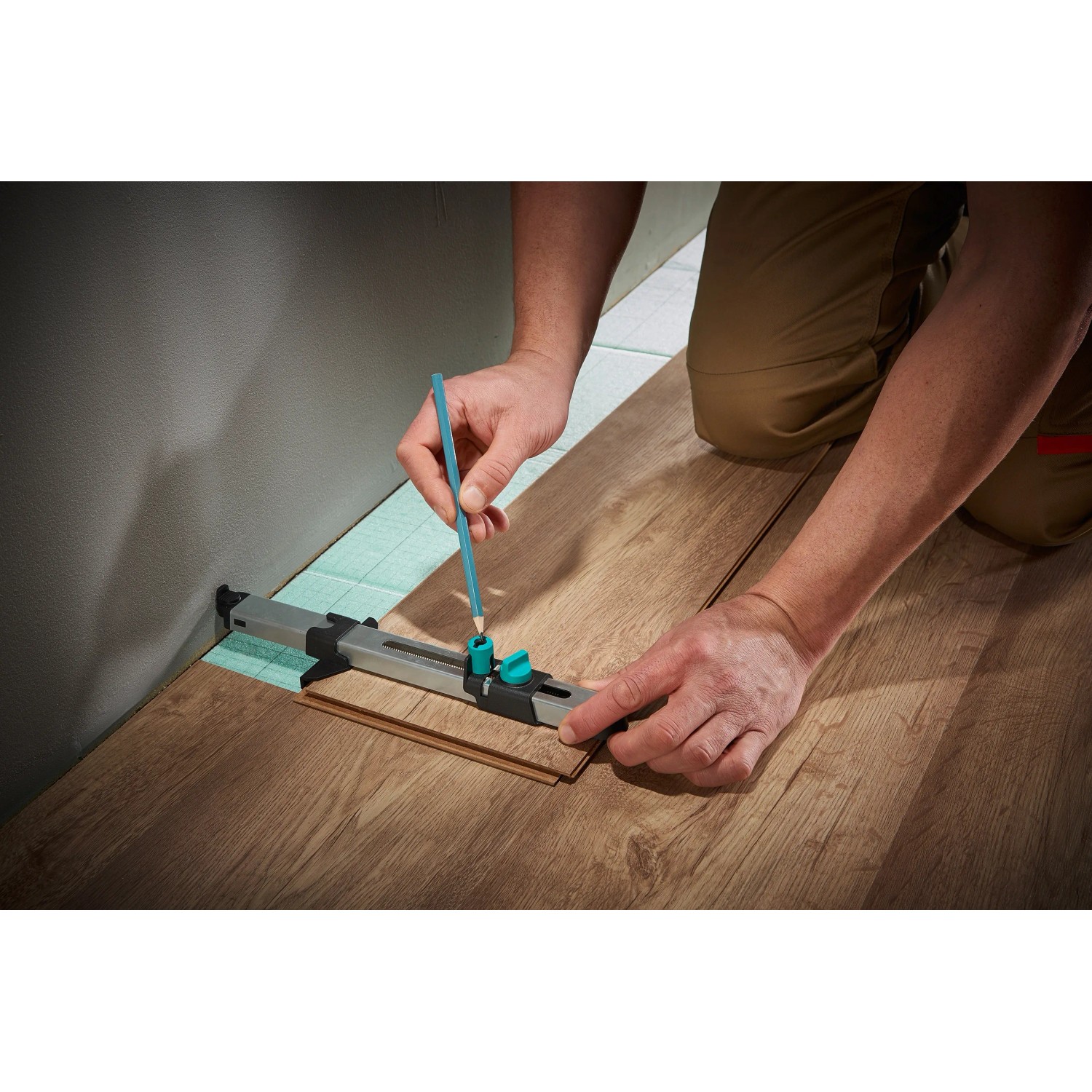 Wolfcraft sada pre montáž laminátu: Remeselník označuje laminát montážnym nástrojom proti stene. Wolfcraft sada pre montáž laminátu: Remeselník označuje laminát montážnym nástrojom proti stene.