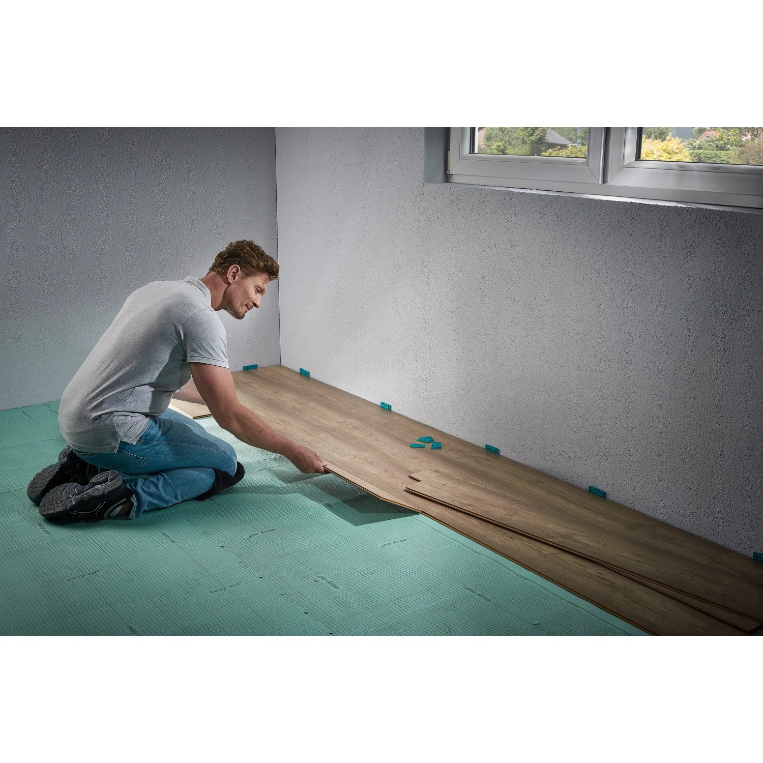 Muž pokladá laminát pomocou súpravy wolfcraft pre laminátové a dizajnové podlahy. Muž pokladá laminát pomocou súpravy wolfcraft pre laminátové a dizajnové podlahy.