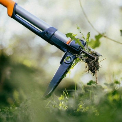 Ergonomický vytrhávač buriny Fiskars v oranžovo-čiernej farbe odstraňuje burinu. Ergonomický vytrhávač buriny Fiskars v oranžovo-čiernej farbe odstraňuje burinu.