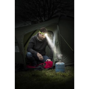 Muž kempuje s LED čelovkou Energizer Vision HD+ pred stanom a lampou.
