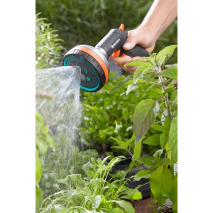Gardena Premium Multibrause v akcii: Ruka drží záhradný postrekovač, prúd vody zavlažuje rastliny.
