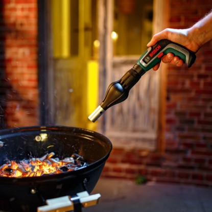 Sada akumulátorového skrutkovača Bosch IXO 7 s nadstavcom na zapaľovanie grilu používaná nad grilom na drevené uhlie.