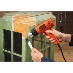 Teplovzdušná pištoľ Black+Decker KX1650 (1 750 W) odstraňuje farbu z okenného rámu.