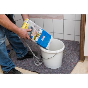 Používateľ sype sivé lepidlo Knauf Flexkleber Schnell z 5 kg vreca do vedra.