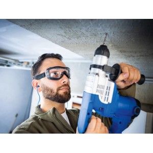 Muž s ochrannými okuliarmi LUX-TOOLS čierno-priehľadnými vŕta do stropu. Odolné proti poškriabaniu a zahmlievaniu s páskou.