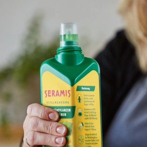 Zelená Seramis Vital výživa pre zelené rastliny a palmy, 500ml fľaša v ruke.