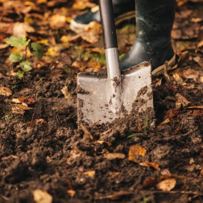 Fiskars Ergonomic rýľ špicatý v akcii: Čepeľ rýľa zapichnutá v zemi, ideálny na kopanie a záhradníčenie.