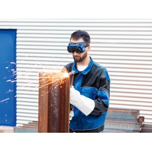 Muž s ochrannými zváračskými okuliarmi LUX-TOOLS stupeň 5 reže kov. Iskry. Ochrana očí.