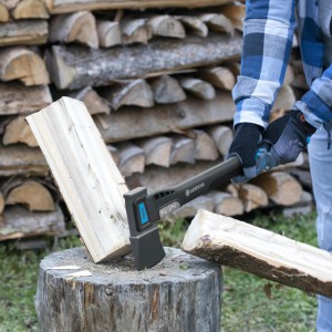 Gardena Universalaxt 1400A štiepa drevo na kláte pred hromadou dreva.