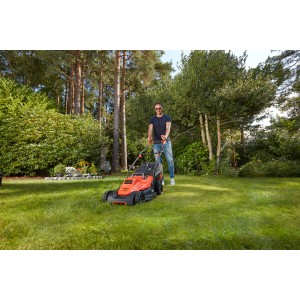 Elektrická kosačka Black+Decker BEMW481BH v akcii: Muž kosí trávnik v záhrade.