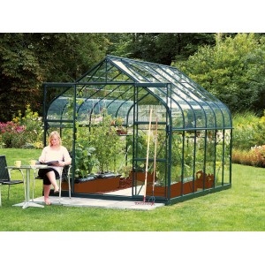 Skleník Vitavia Diana 9900 zelený so ženou pred ním, 9,9 m² pestovateľskej plochy.