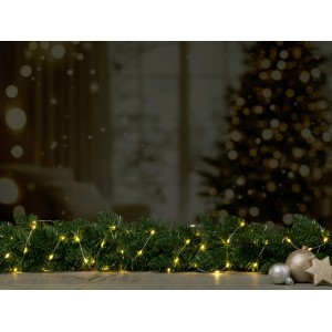 Teplá biela mini LED svetelná reťaz (240 LED) na jedľovej zeleni s dekoratívnymi prvkami pred vianočným stromčekom.