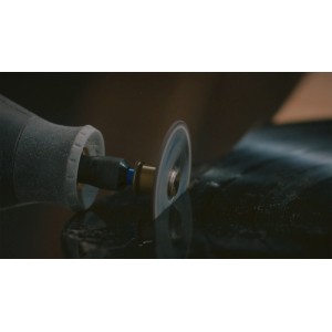 Rotačný nástroj Dremel s rezacím kotúčom EZ SpeedClic presne reže tmavý povrch.