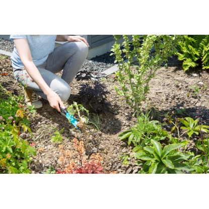 Záhradníčka odstraňuje burinu pomocou vypichovača buriny Gardena v záhrade.