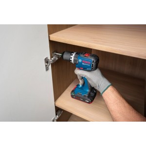 Aku vŕtací skrutkovač Bosch GSB18V-52 montuje pánt do skrinky. Kompaktné akumulátorové náradie na montáž.