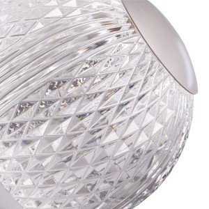 Detail nočnej lampy s čírym, fasetovaným skleneným tienidlom.