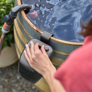 Akumulátorové čerpadlo do dažďového suda Gardena 2400 ComfortAutomatic na sude s rukou na ovládacích prvkoch.