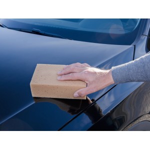 Ruka čistí auto obdĺžnikovou umývacou hubkou CMI. Starostlivosť o auto pre šetrné čistenie.