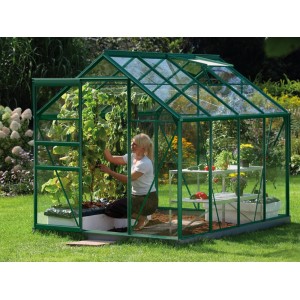 Zelený skleník Vitavia Venus 5000 so ženou starajúcou sa o rastliny v záhrade.