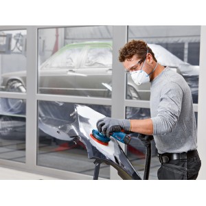 Muž brúsi diel karosérie akumulátorovou excentrickou brúskou Bosch GEX 12V-125. Brúska s odsávaním prachu.