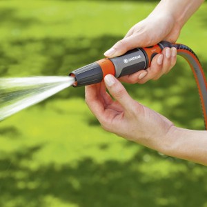 Čistiaci postrekovač Gardena v akcii: vodný lúč na čistenie záhrady.