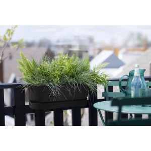Čierny závesný kvetináč Elho Greenville Easy Balcony (52 cm) s rastlinami na balkónovom zábradlí.