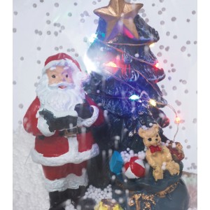 Hudobná snehová guľa: Santa Claus, osvetlený strom s farebnými LED svetlami, darčeky. Slávnostná vianočná dekorácia.