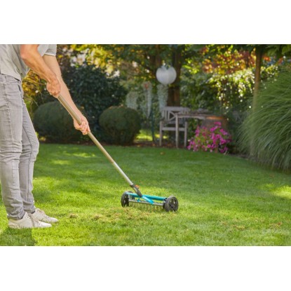 Gardena Combisystem vertikutátor v použití: Odstraňovanie machu v záhrade s pracovnou šírkou 32 cm.