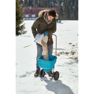 Muž plní posypový vozík Gardena XL posypovým materiálom v zime. Univerzálny posypový vozík.